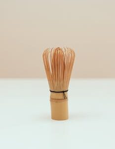 A close-up of a traditional bamboo tea whisk against a simple backdrop, perfect for ceremonies.